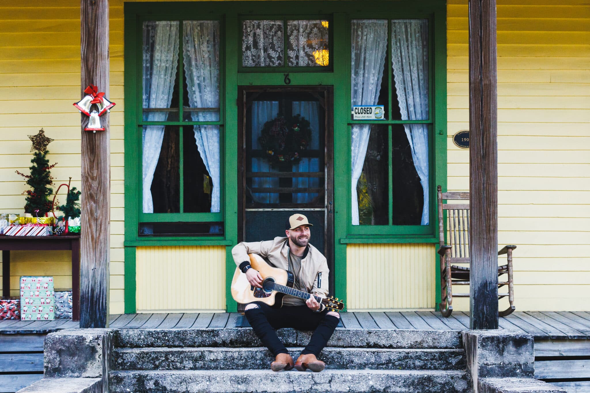 Ralph Curtis playing guitar on a sunlit porch